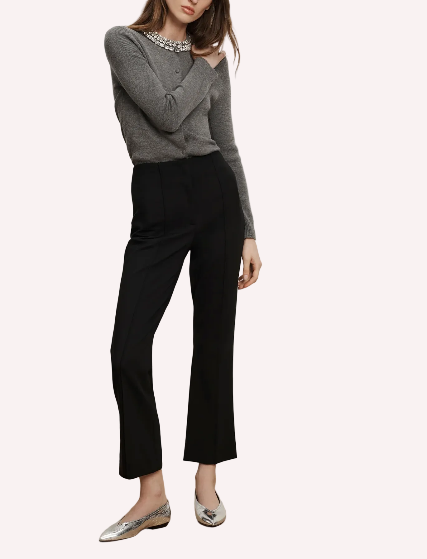 Person wearing a gray sweater and black pants on a plain background