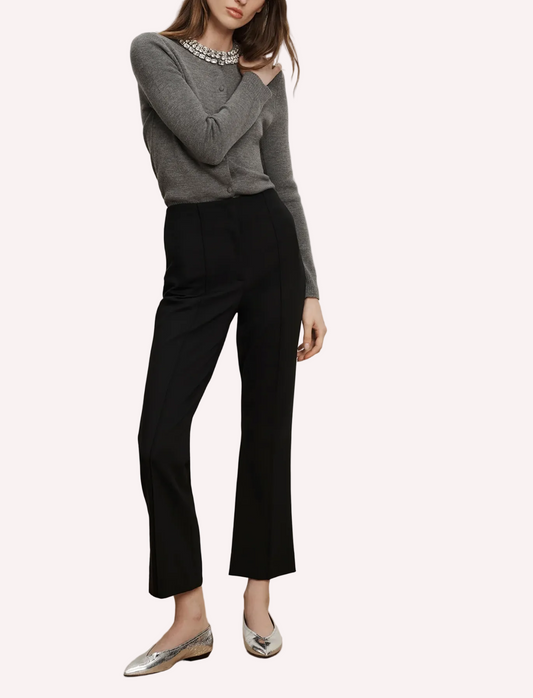 Person wearing a gray sweater and black pants on a plain background