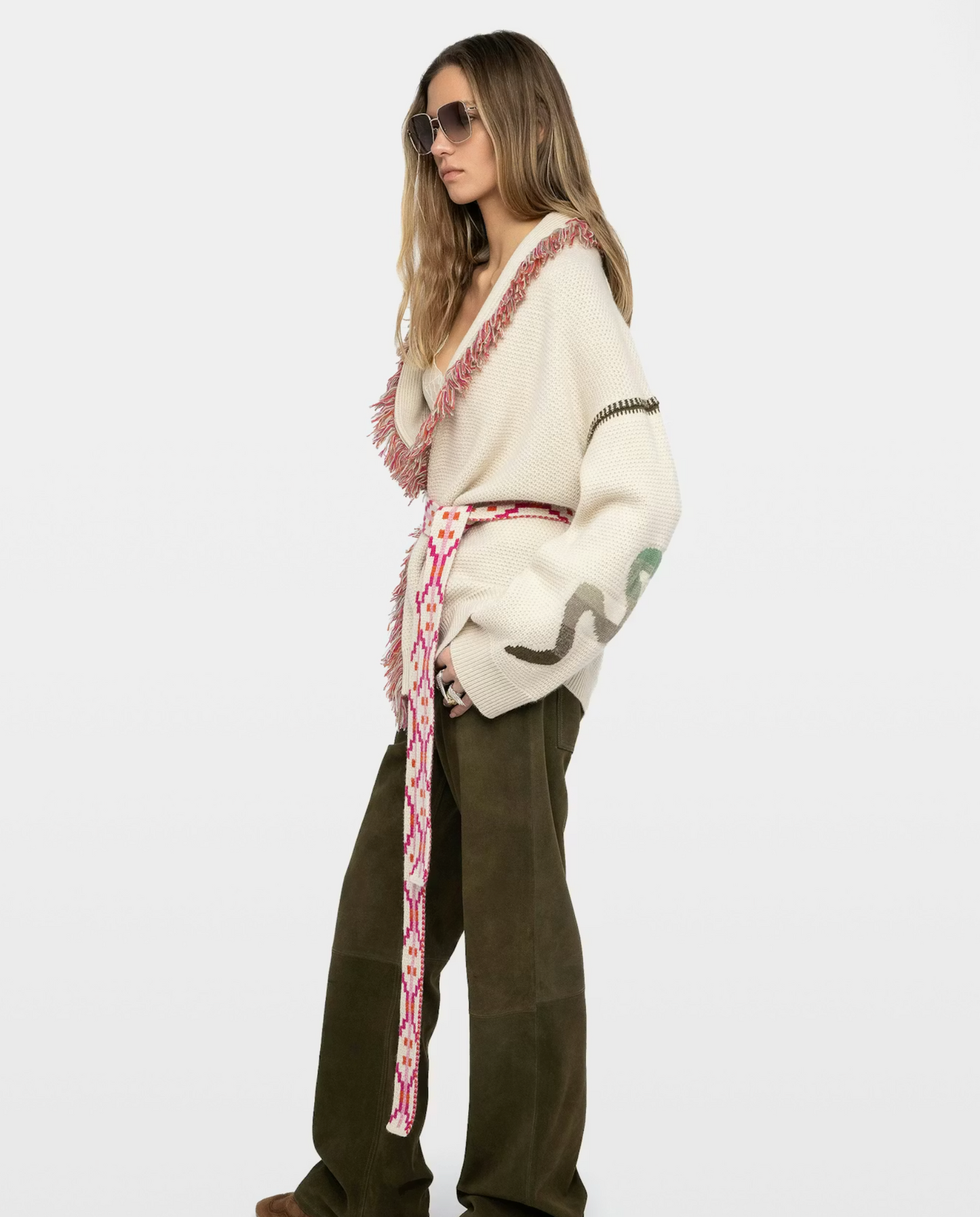 Woman wearing a patterned sweater and green pants on a white background