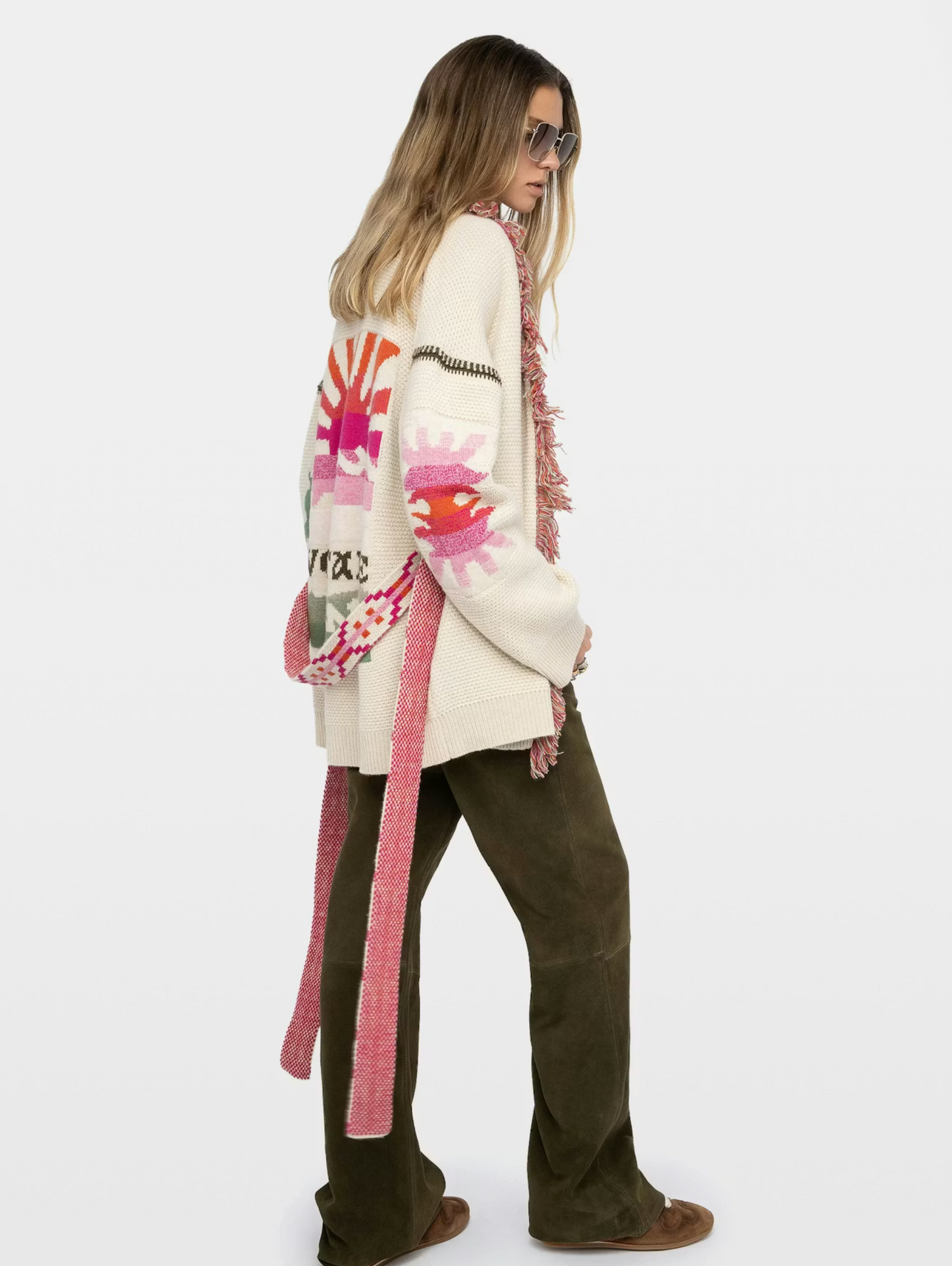 Person wearing a colorful cardigan with a pattern and text, standing against a white background