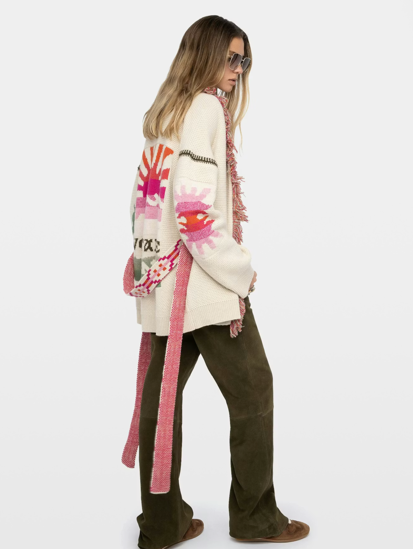 Person wearing a colorful cardigan with a pattern and text, standing against a white background