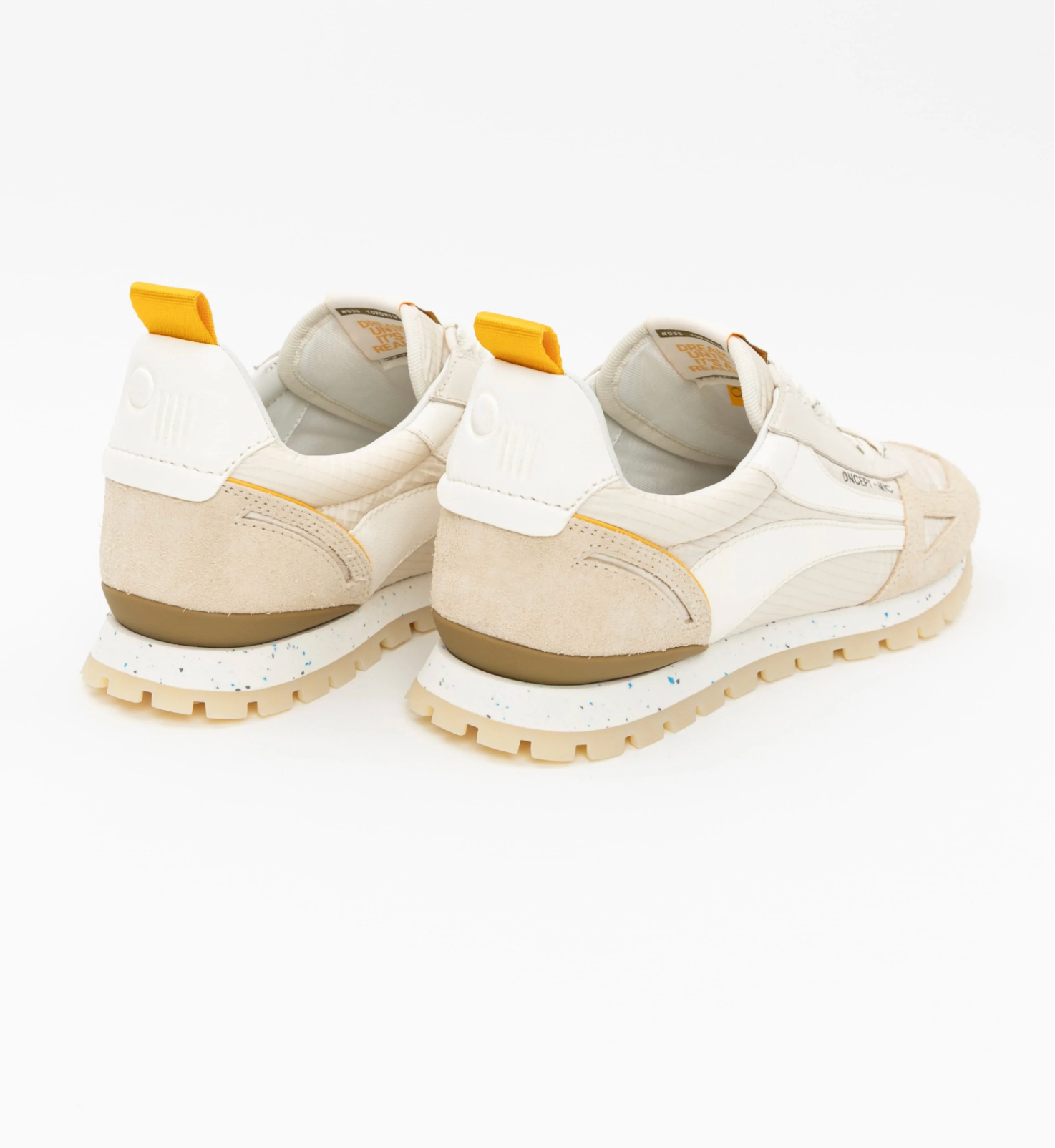 Pair of beige sneakers with yellow accents on a white background