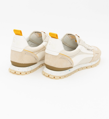 Pair of beige sneakers with yellow accents on a white background