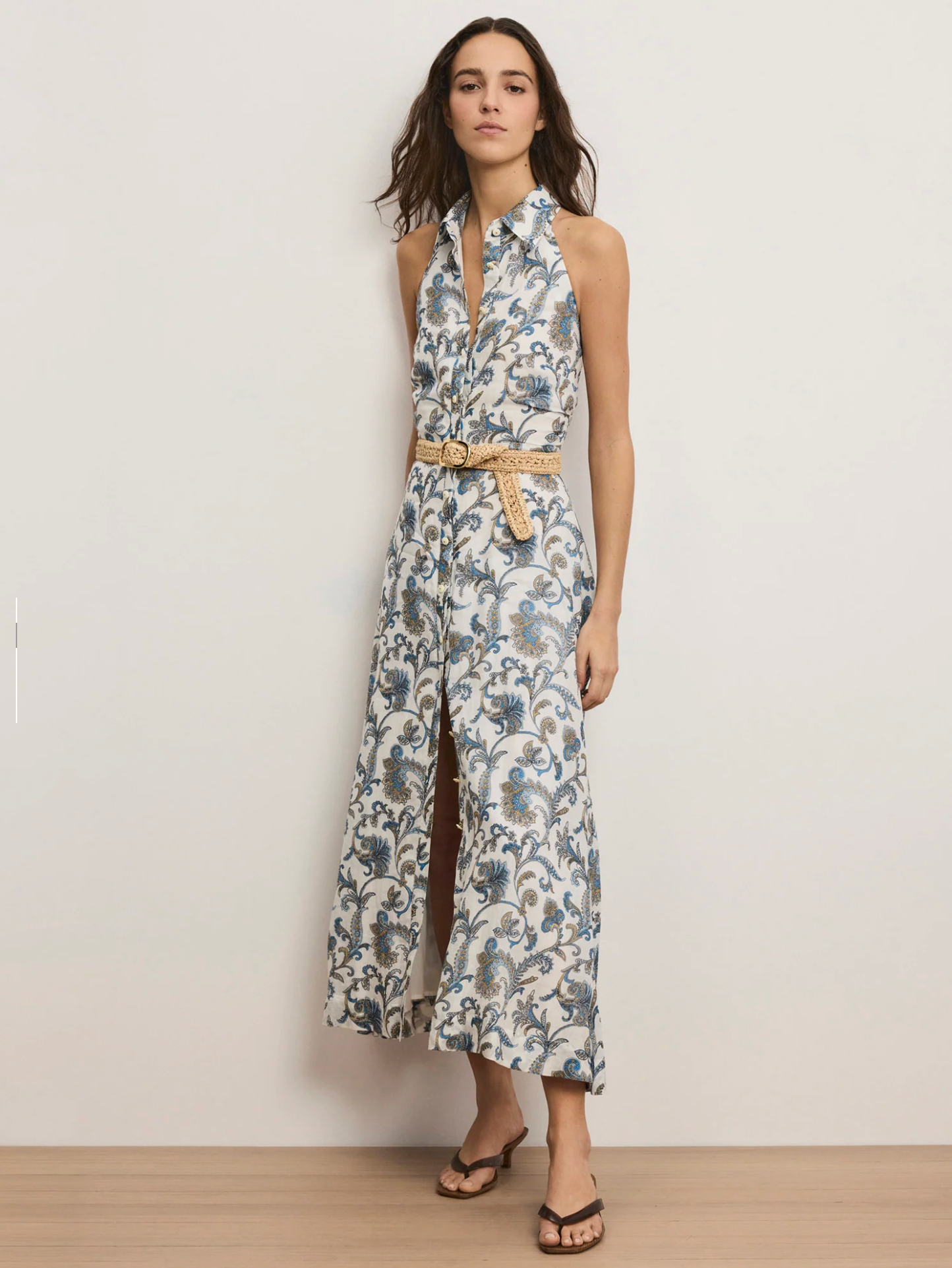 Woman wearing a floral dress with a belt against a plain background