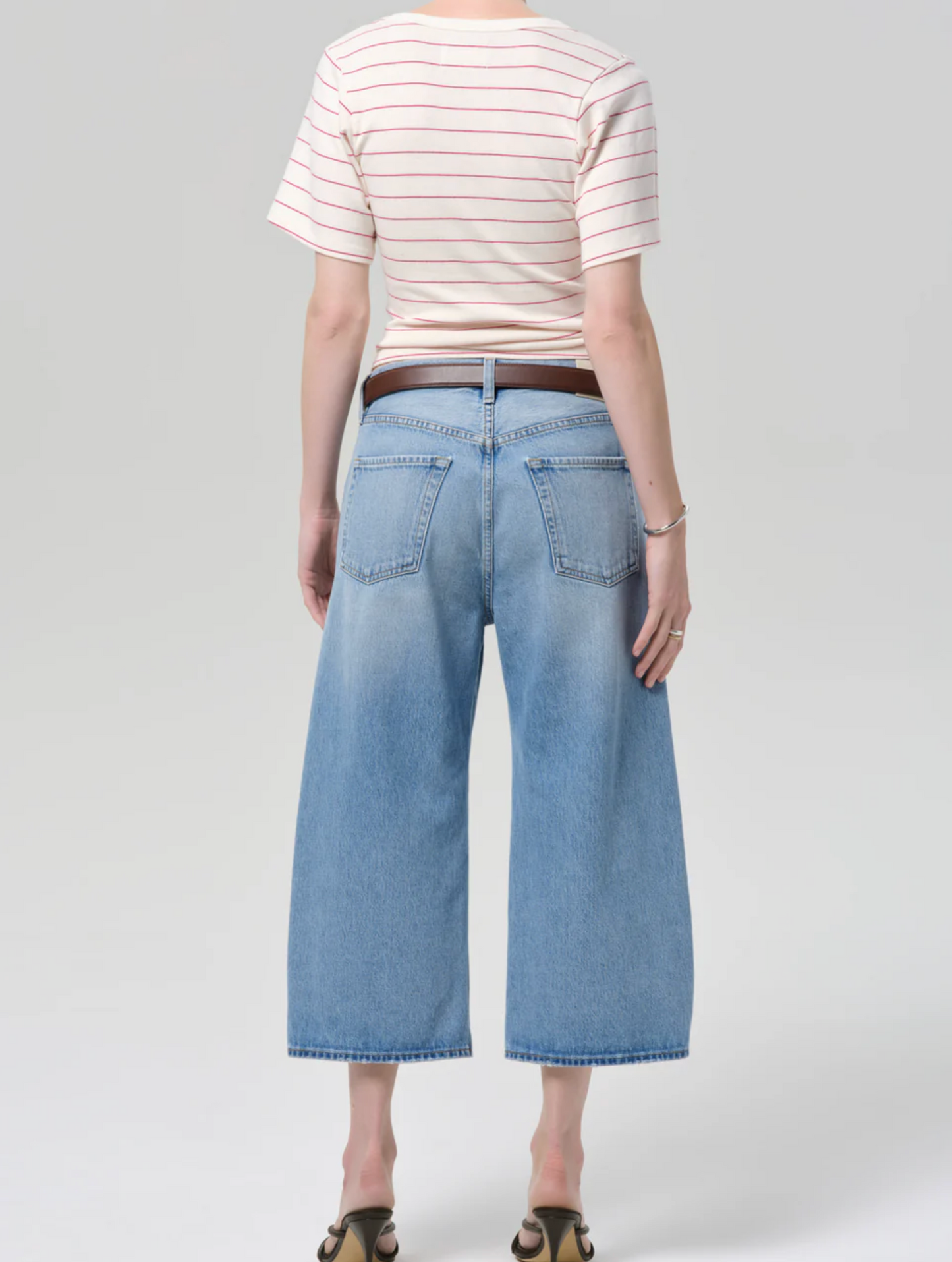 Person wearing a striped shirt and light blue wide-leg jeans on a white background