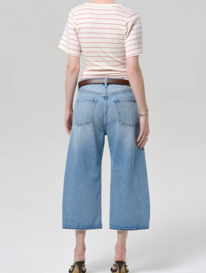 Person wearing a striped shirt and light blue wide-leg jeans on a white background
