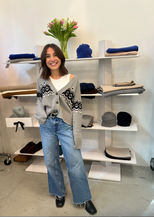 Woman posing in a store with shelves displaying various items