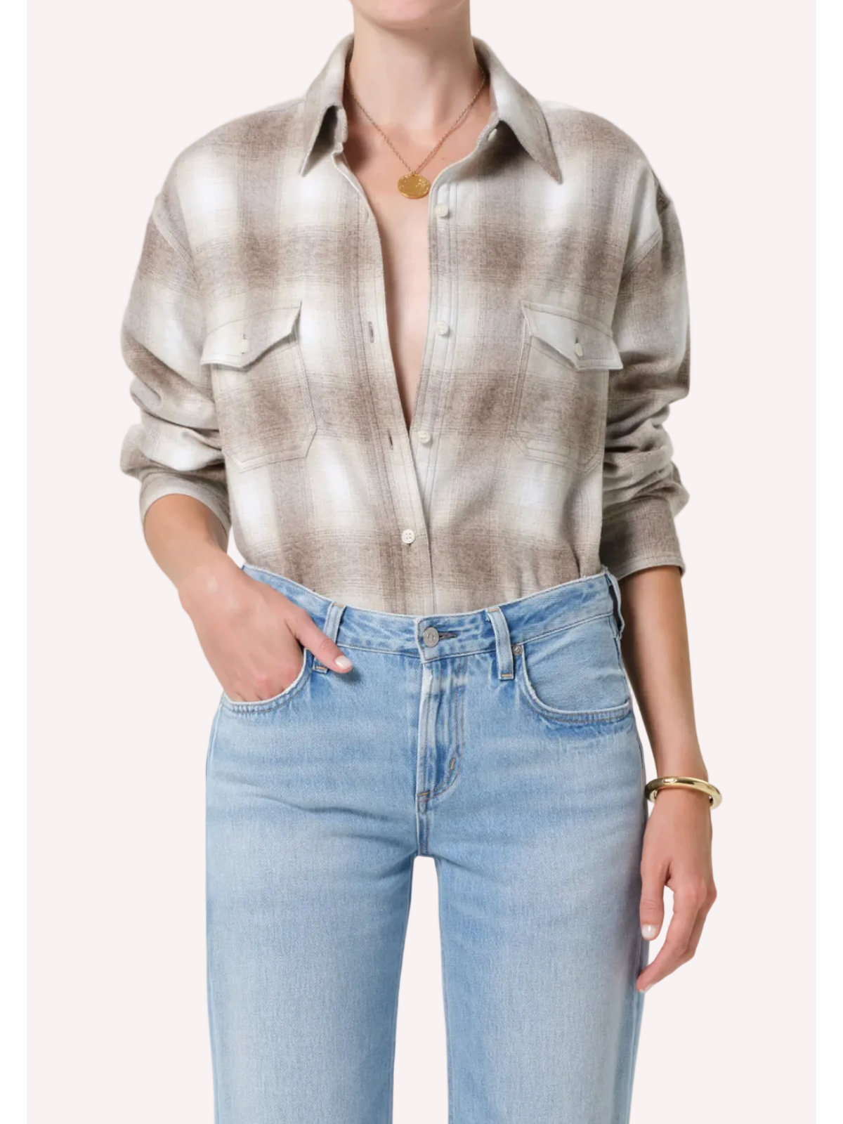 Person wearing a patterned shirt and light blue jeans on a plain background
