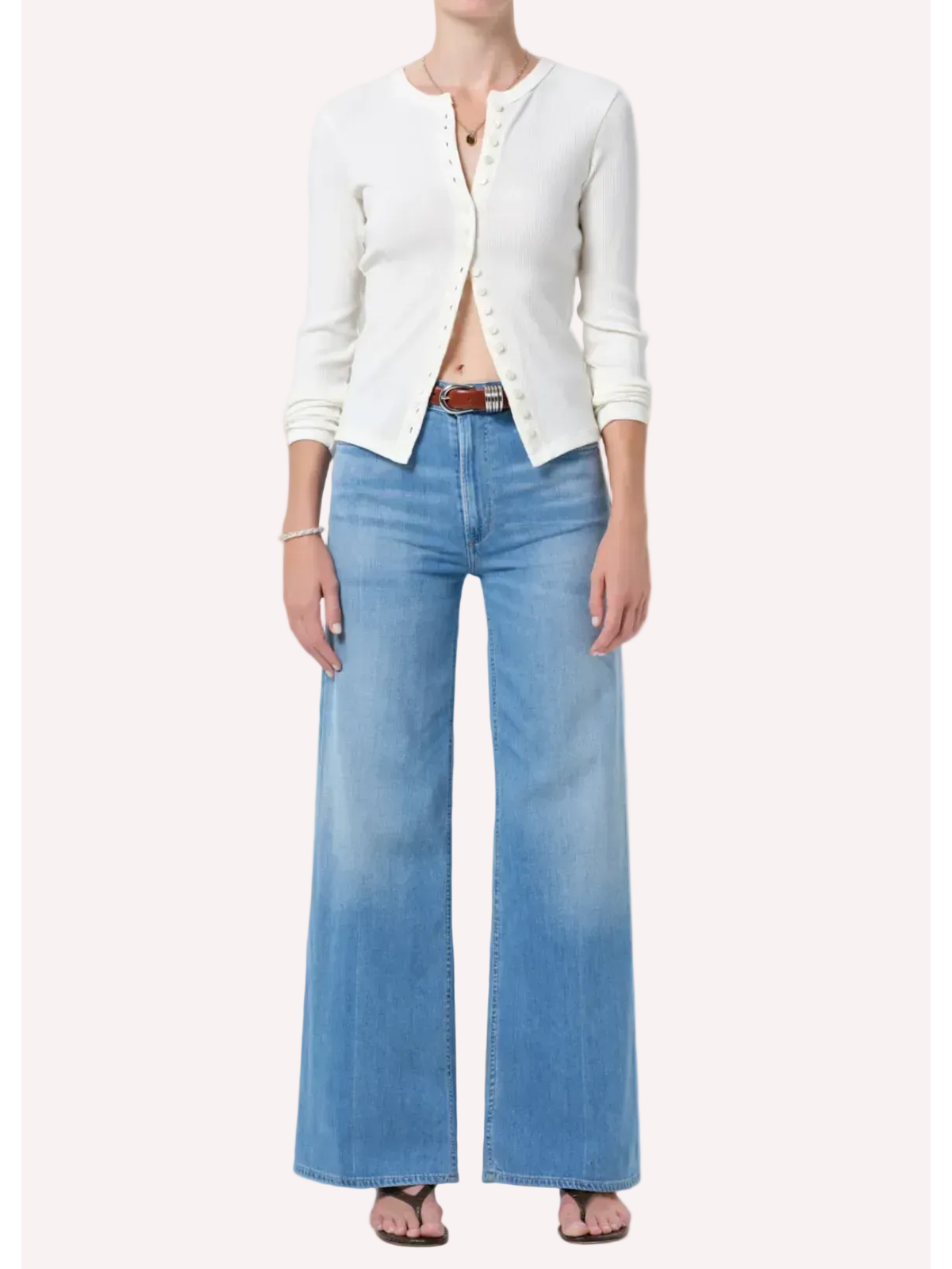 Person wearing a white cardigan and blue jeans on a plain background