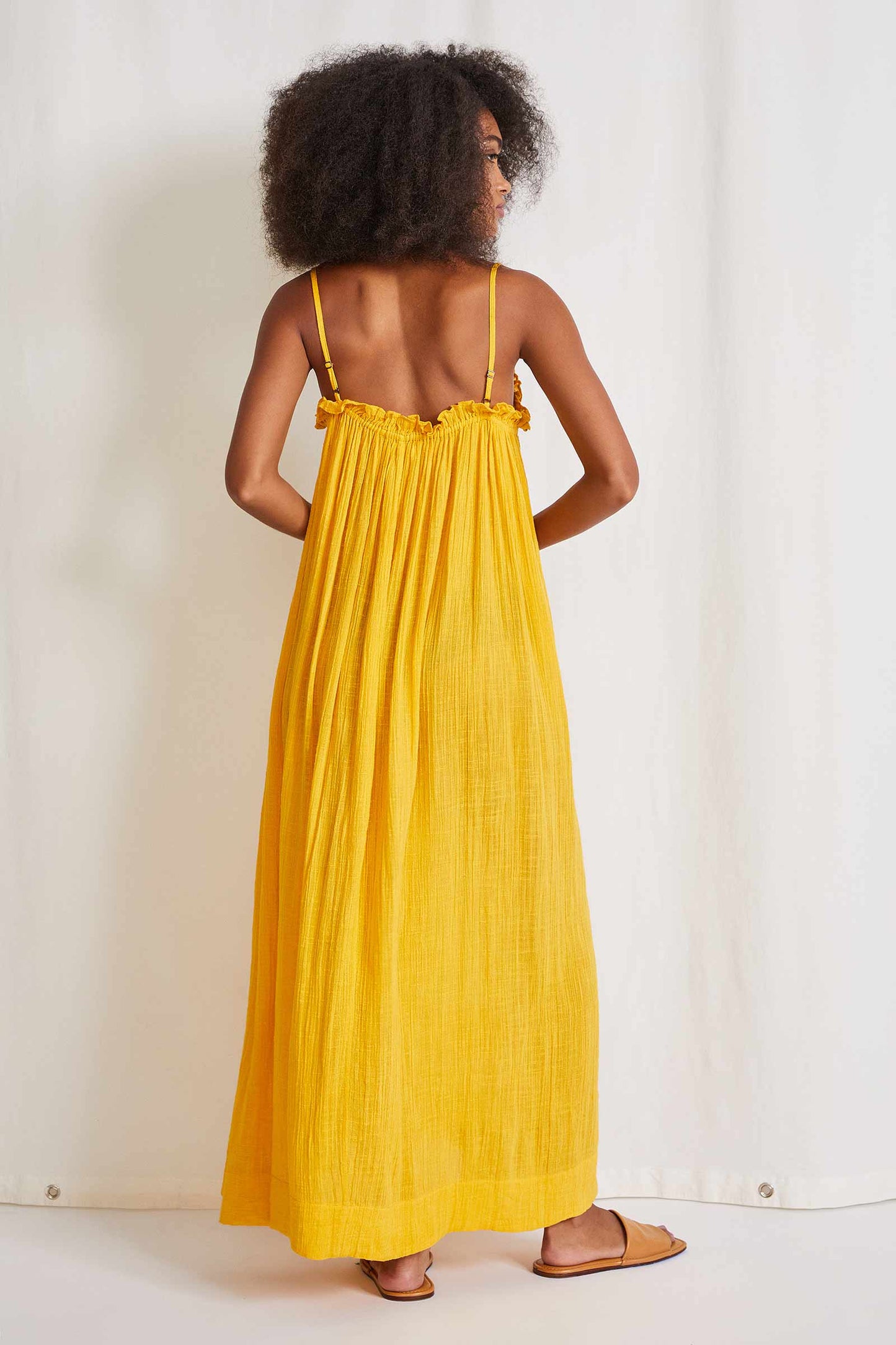 This beautiful spaghetti strap maxi dress is completes with gathered elastic around the chest and a ruffle detail. This dress is lined and made of a cotton blend. Comes in mimosa  and charcoal hues.